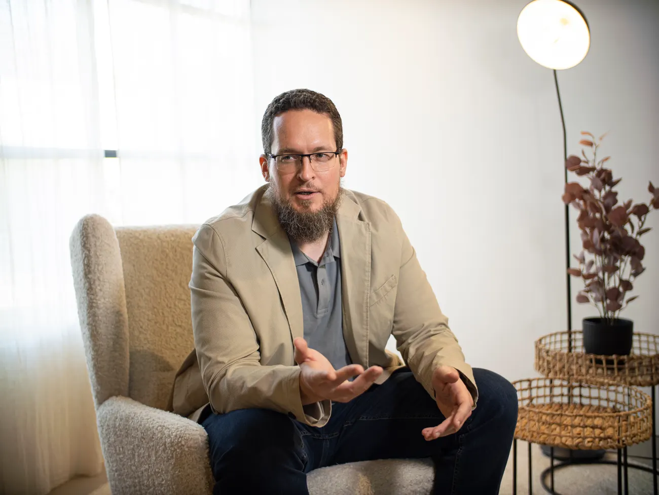 Muhammad Kasprowicz seated in an armchair, mid-conversation.